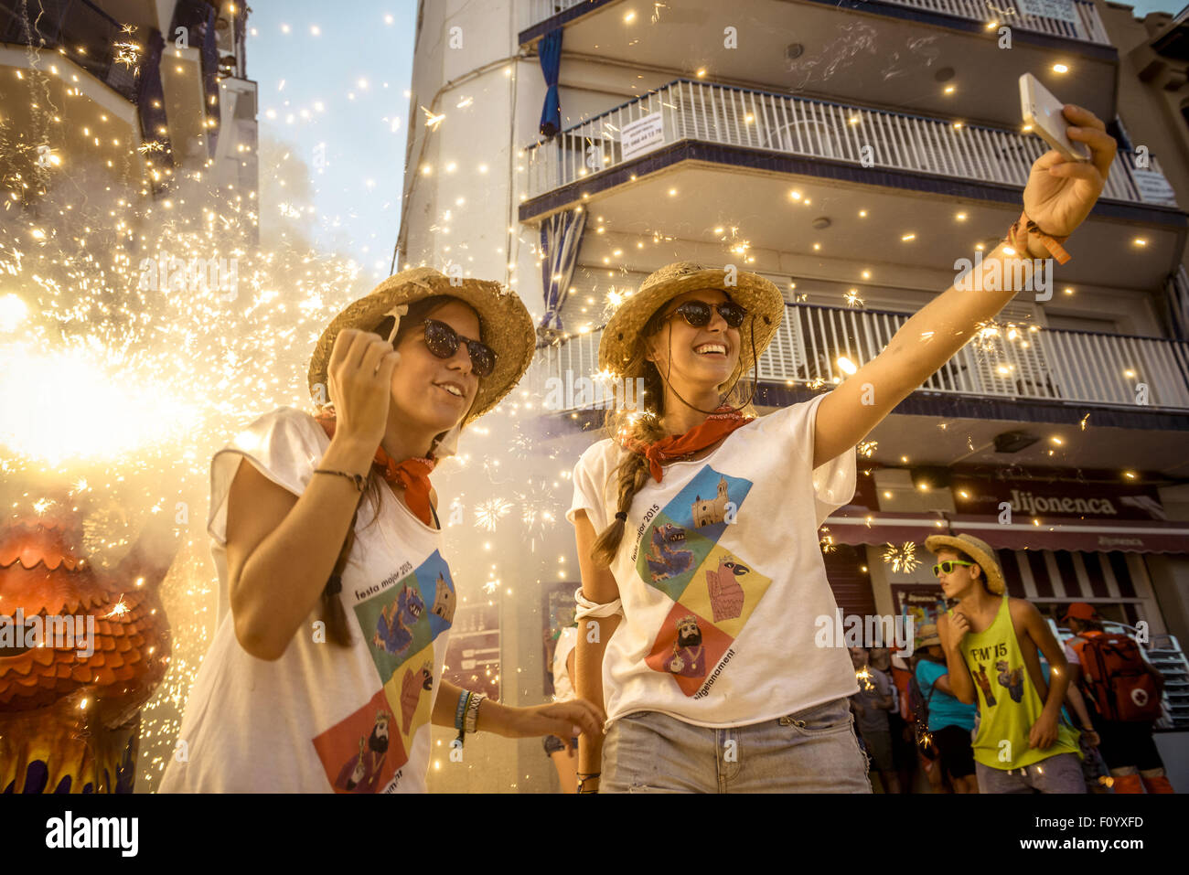 Sitges, Catalogna, Spagna. 23 Ago, 2015. Due ragazze prendere un 'selfie' come 'Aliga (Aquila) de Sitges', un simbolo folcloristico, set fuori i suoi fuochi d'artificio tra la folla di spettatori a 'Festa Major de Sitges' Credit: Matthias Oesterle/ZUMA filo/Alamy Live News Foto Stock