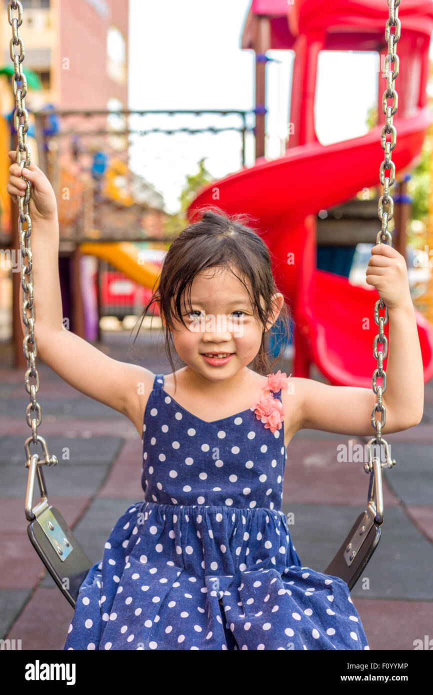 Ragazza giovane giocando swing sul parco giochi con la felicità. Foto Stock