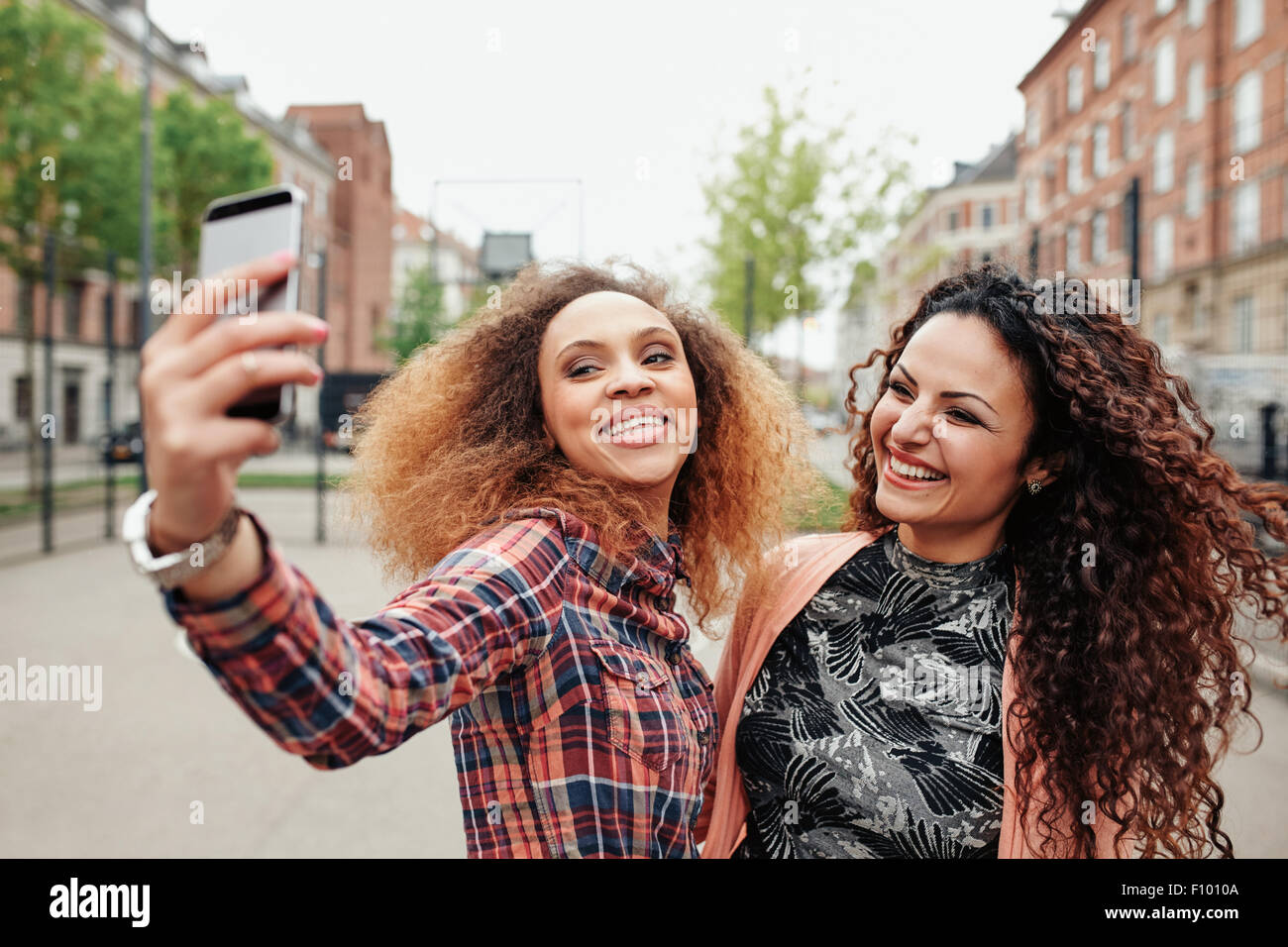 Due belle giovani donne di scattare una foto insieme sulla strada della citta'. Giovani amici di sesso femminile prendendo un selfie tramite telefono cellulare, out Foto Stock