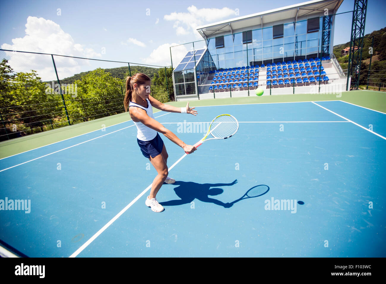 Femmina giocatore di tennis di eseguire un drop shot su una bella corte blu Foto Stock