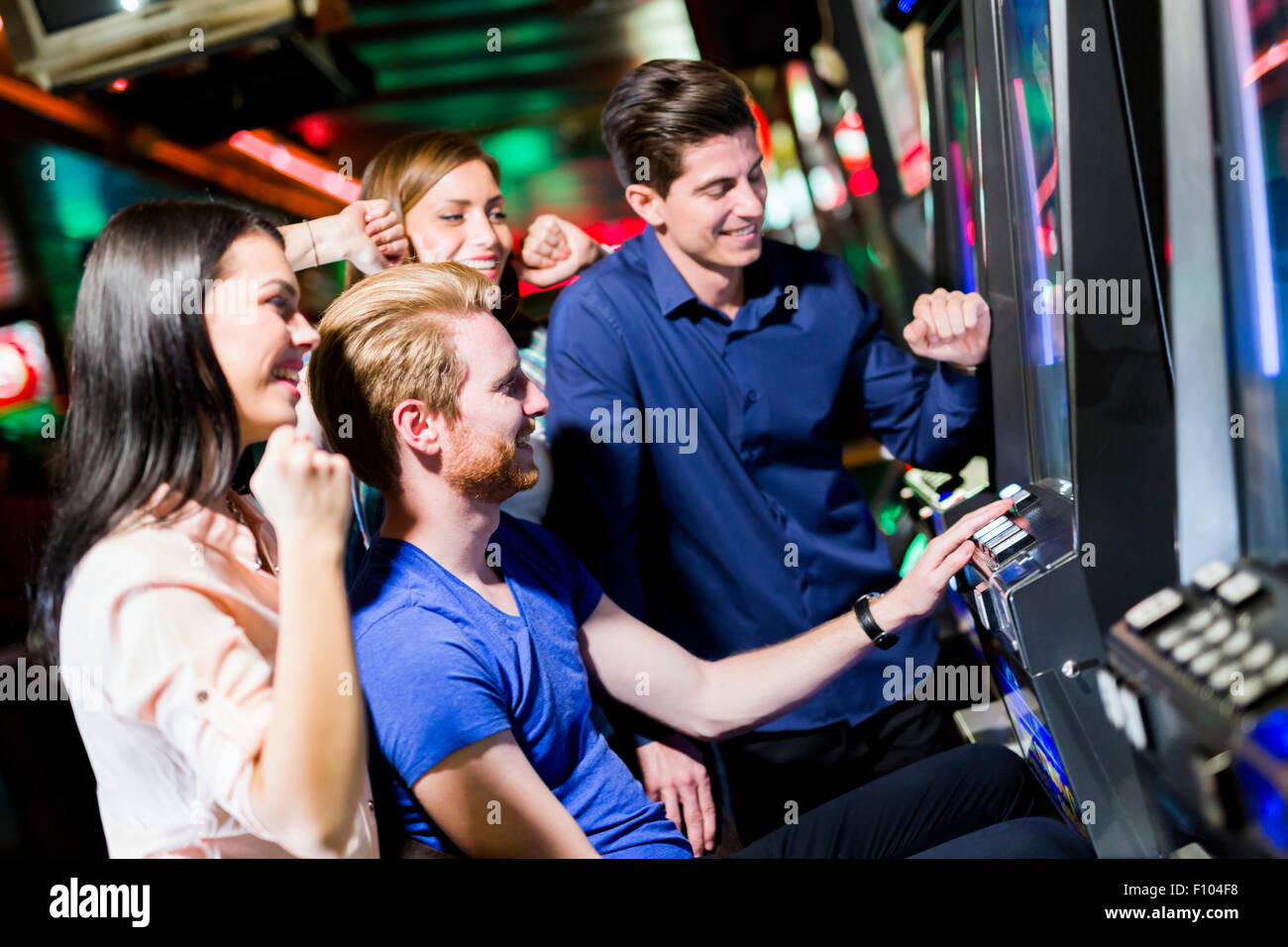 Giovane gruppo di persone il gioco d'azzardo in un casinò giocare slot e macchine varie Foto Stock