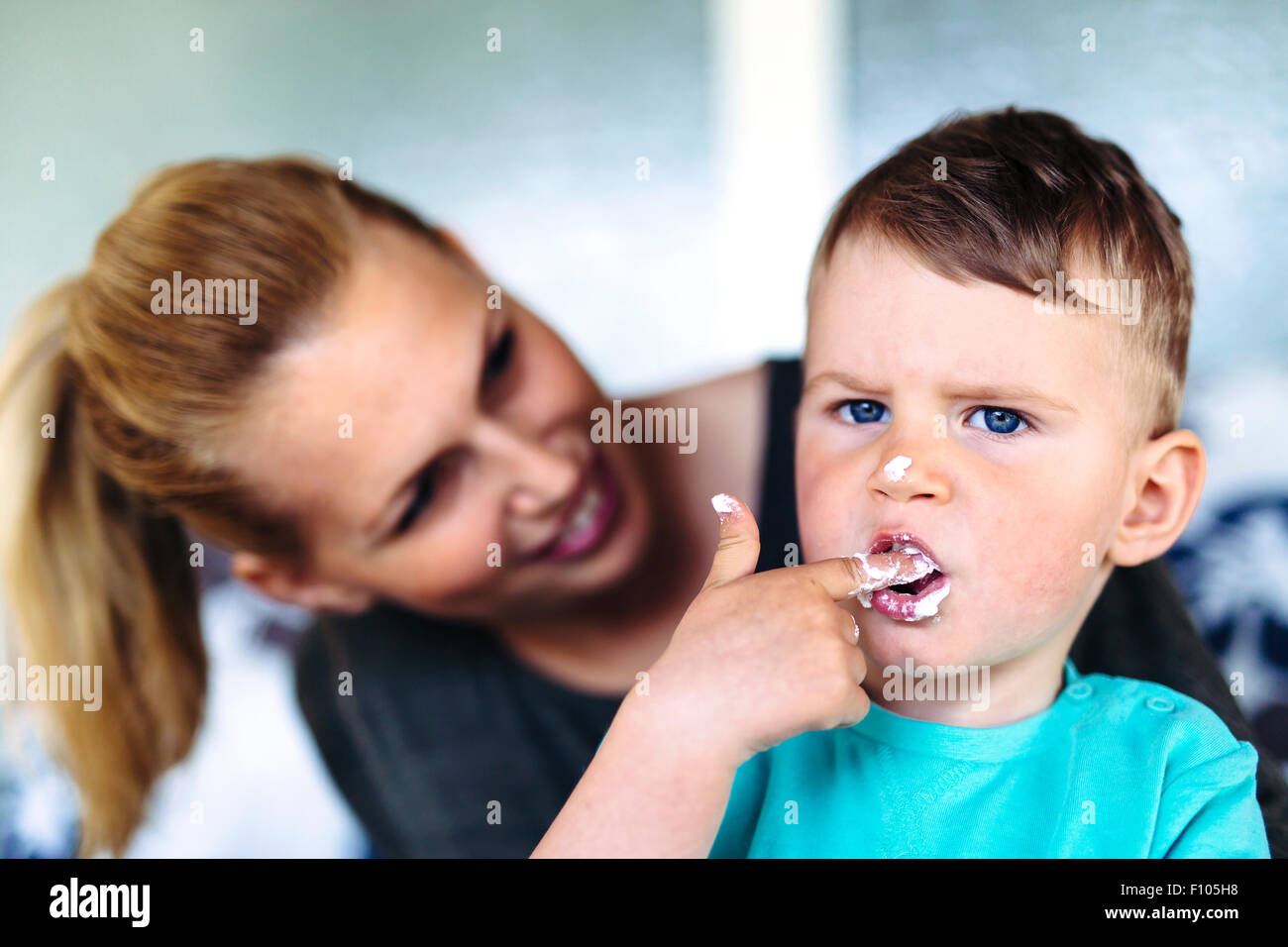 La madre e il bambino a mangiare una torta / deserto con le dita e divertendosi Foto Stock