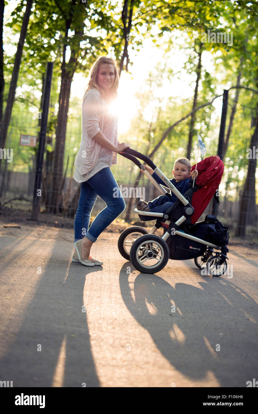 La madre del bambino a piedi in una carrozzina nel parco Foto Stock