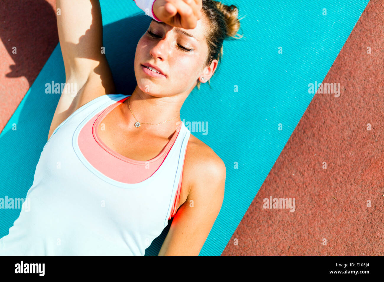 Esaurito bella giovane donna sdraiata su un tappetino dopo esercizio Foto Stock