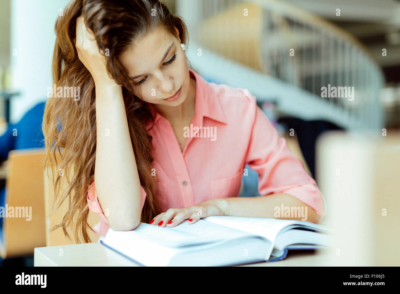 Bella donna focalizzata a studiare in biblioteca Foto Stock