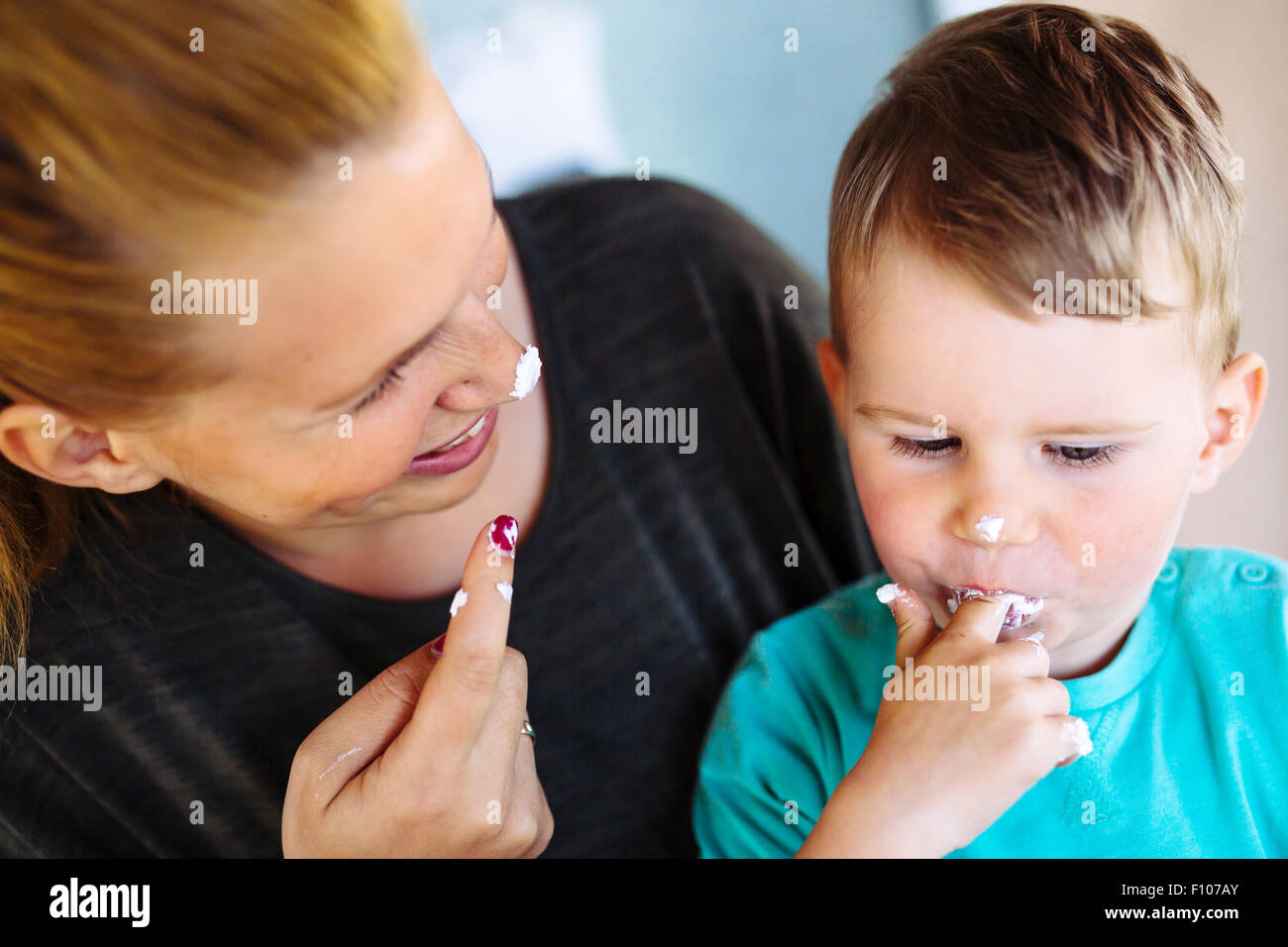 La madre e il bambino a mangiare una torta / deserto con le dita e divertendosi Foto Stock