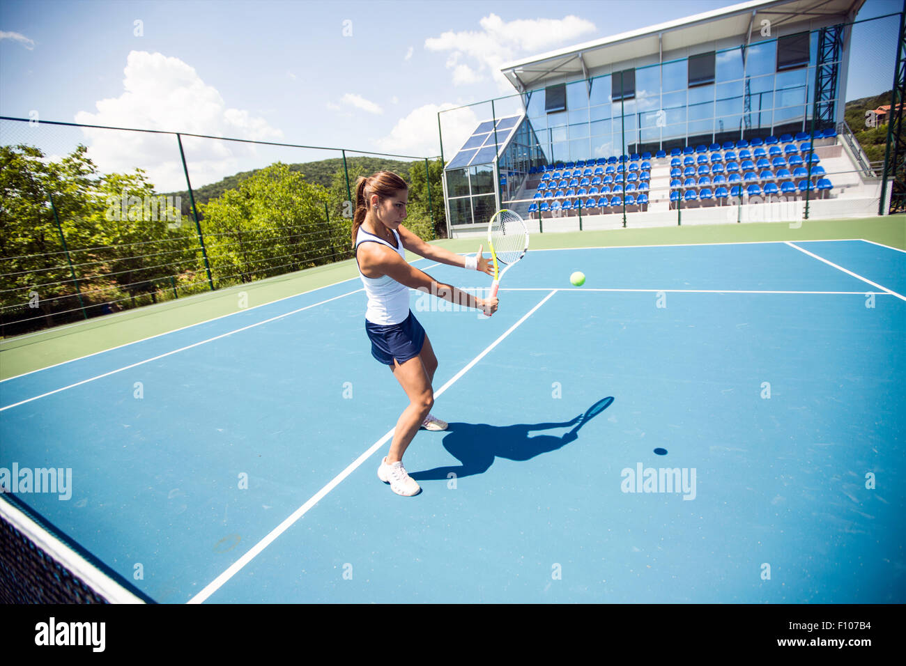 Femmina giocatore di tennis di eseguire un drop shot su una bella corte blu Foto Stock
