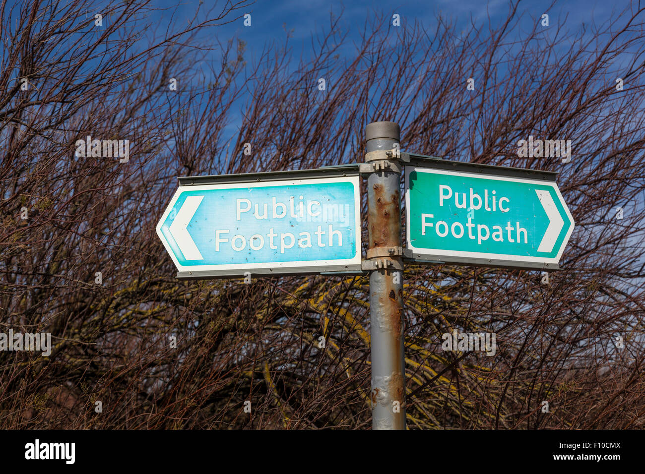 Verde e bianco metallo sentiero pubblico segno su un palo arrugginito, West Sussex. Foto Stock