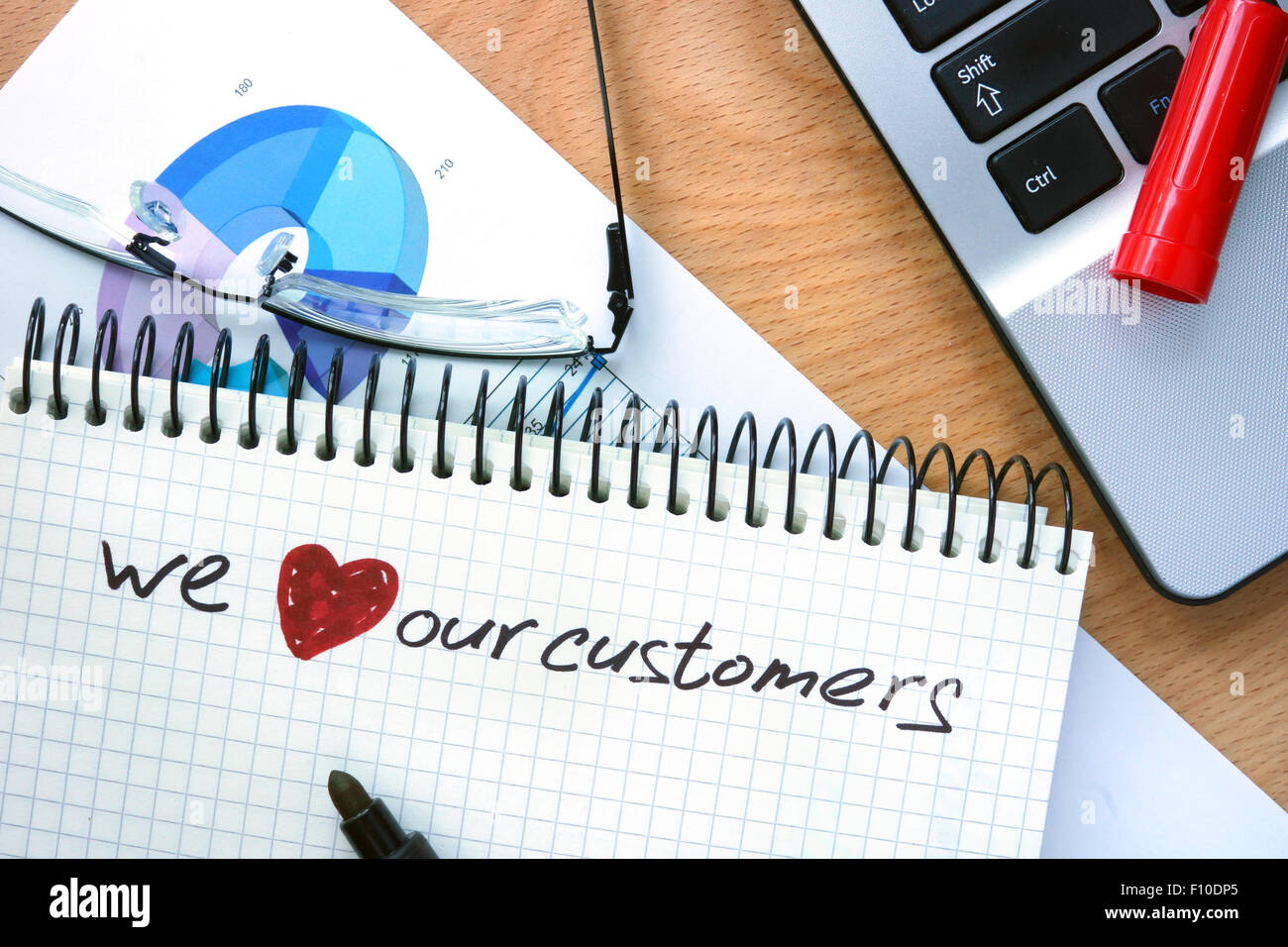 Blocco note con le parole che amiamo i nostri clienti su un sfondo di legno Foto Stock