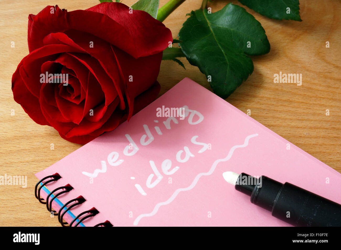 Il blocco note di rosa con idee di nozze e rose su uno sfondo di legno. Foto Stock