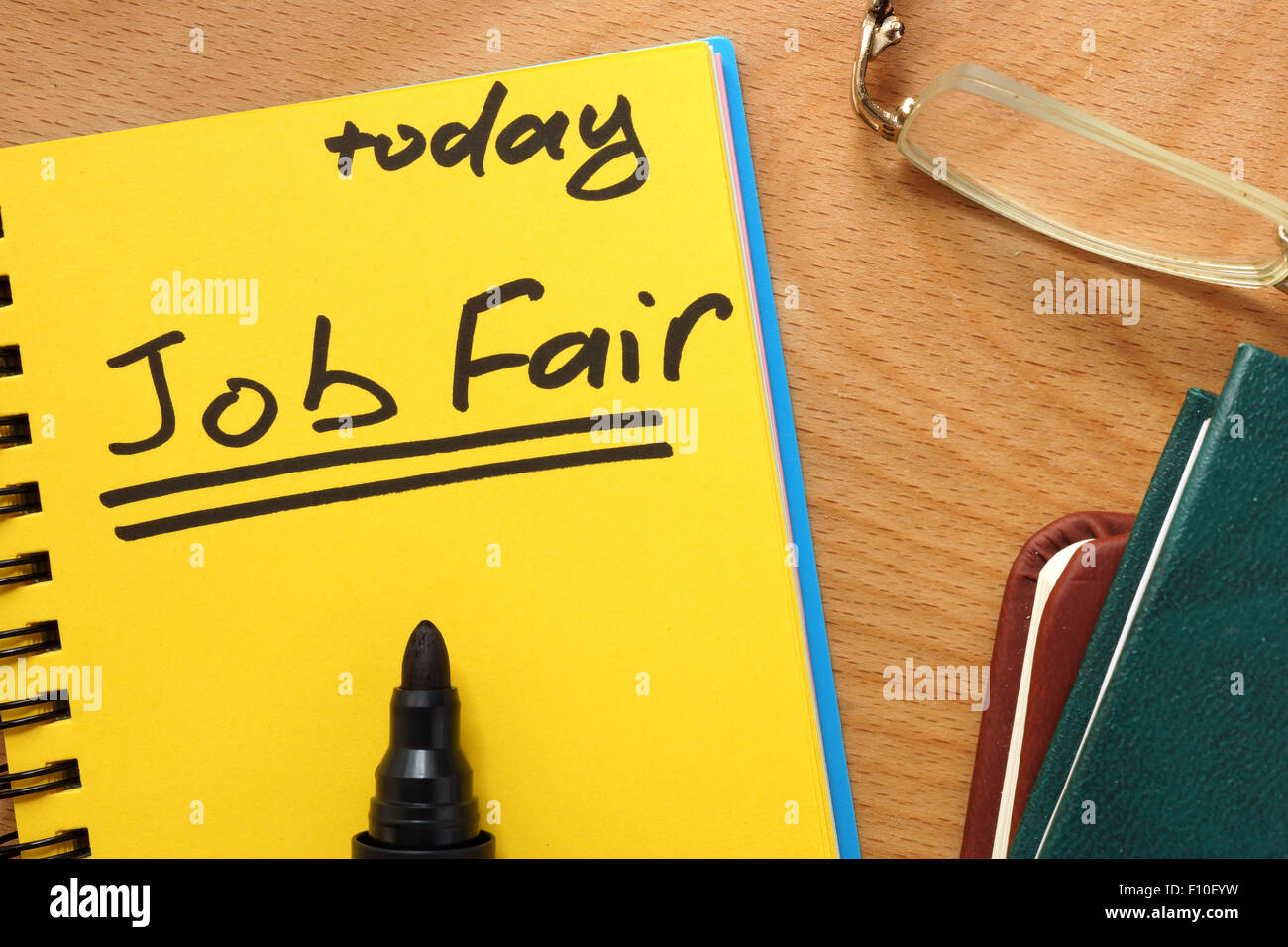 Blocco note con fiera del lavoro su un tavolo di legno. Foto Stock