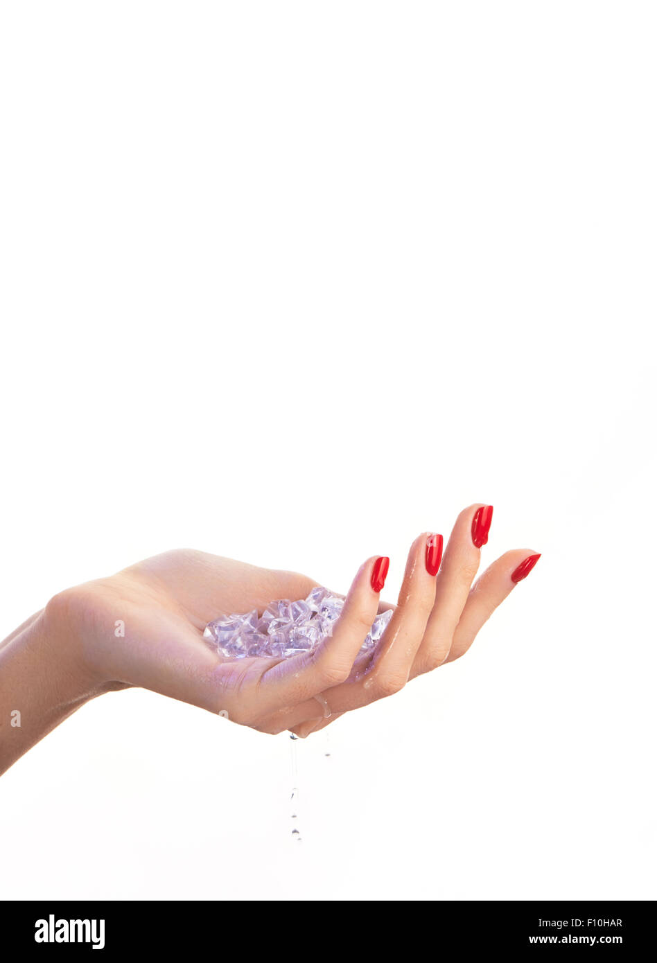 Femmina con mano rosso smalto per unghie, blu di cubetti di ghiaccio al suo interno e gocce di acqua, isolato su sfondo bianco Foto Stock