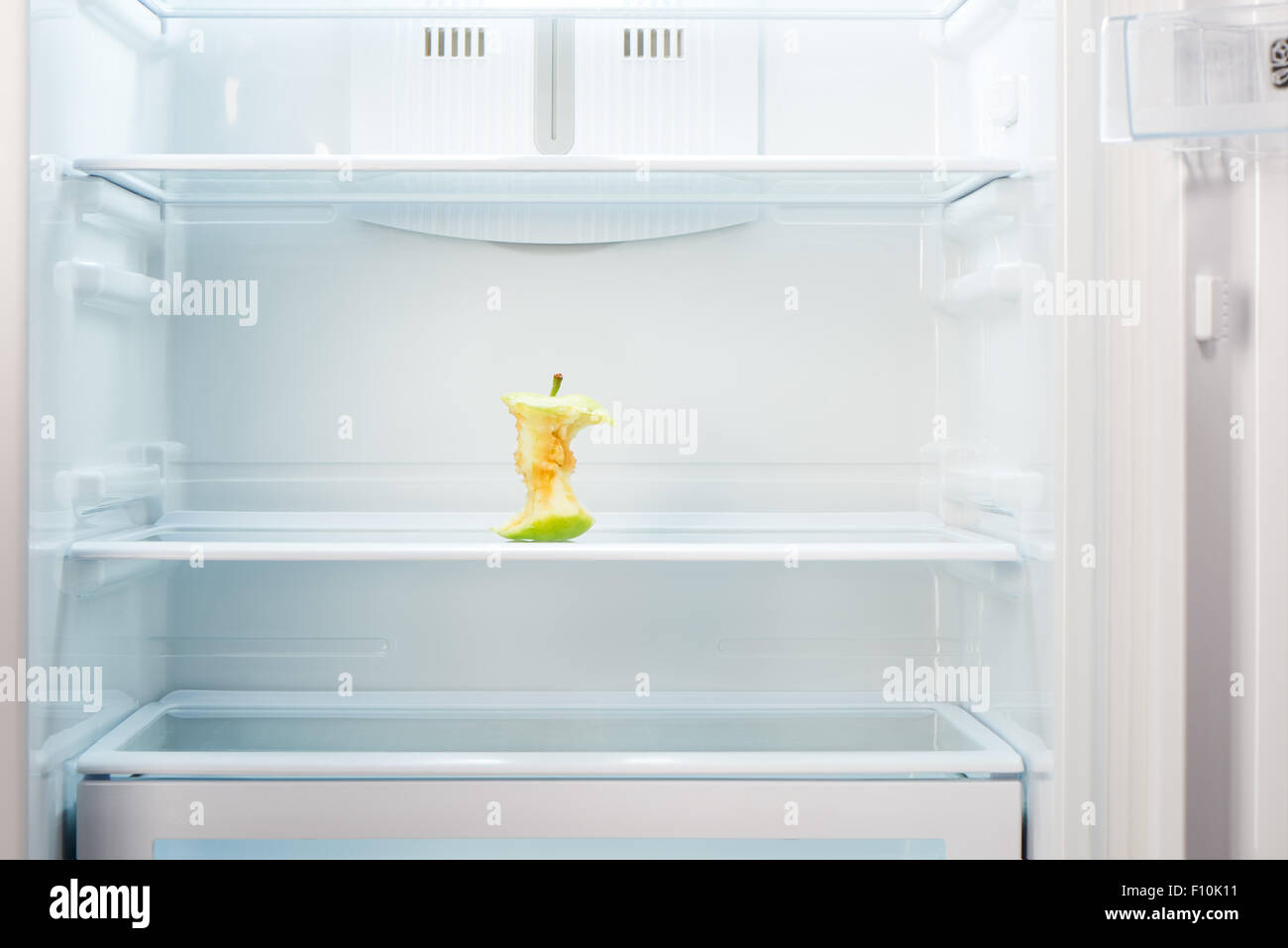 Apple core sul ripiano di aprire un frigorifero vuoto. Perdita di peso la dieta concetto. Foto Stock