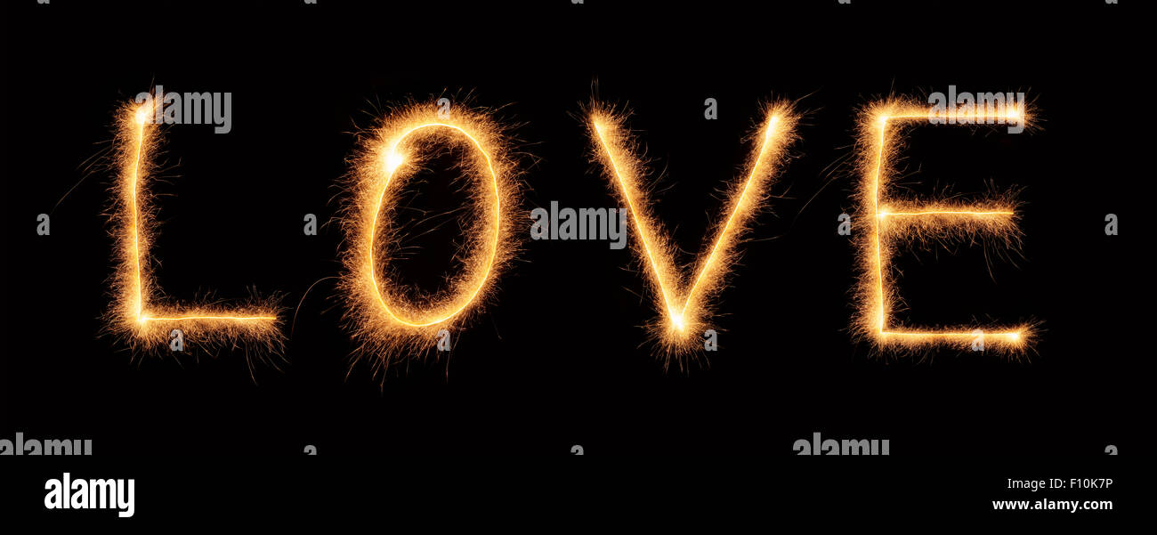'Amore' lettering disegnato con brillantini bengali isolati su sfondo nero Foto Stock