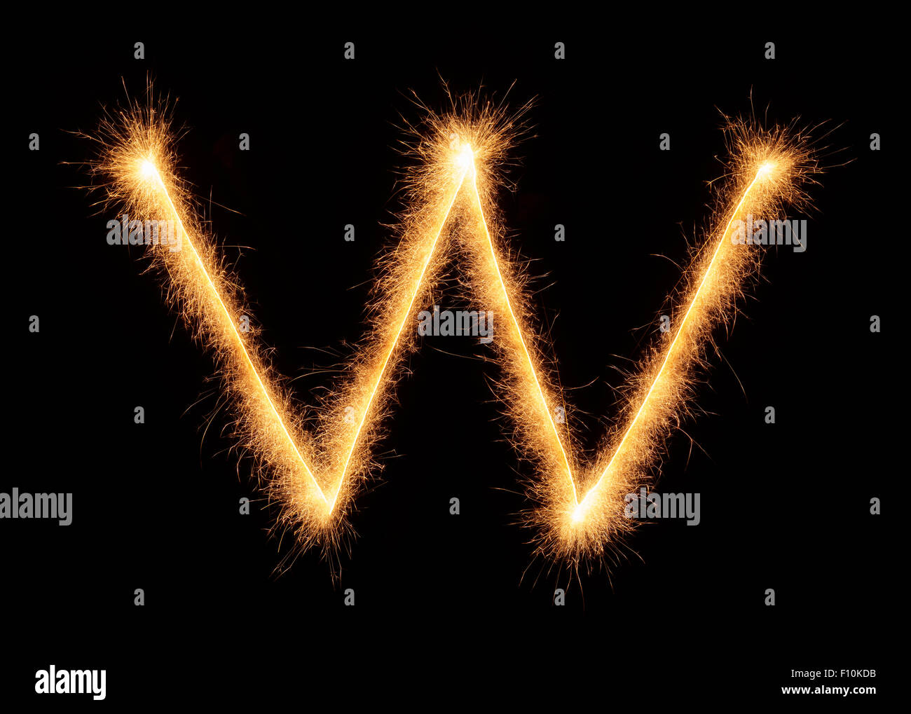 " W " lettera estratta con brillantini bengali isolati su sfondo nero Foto Stock