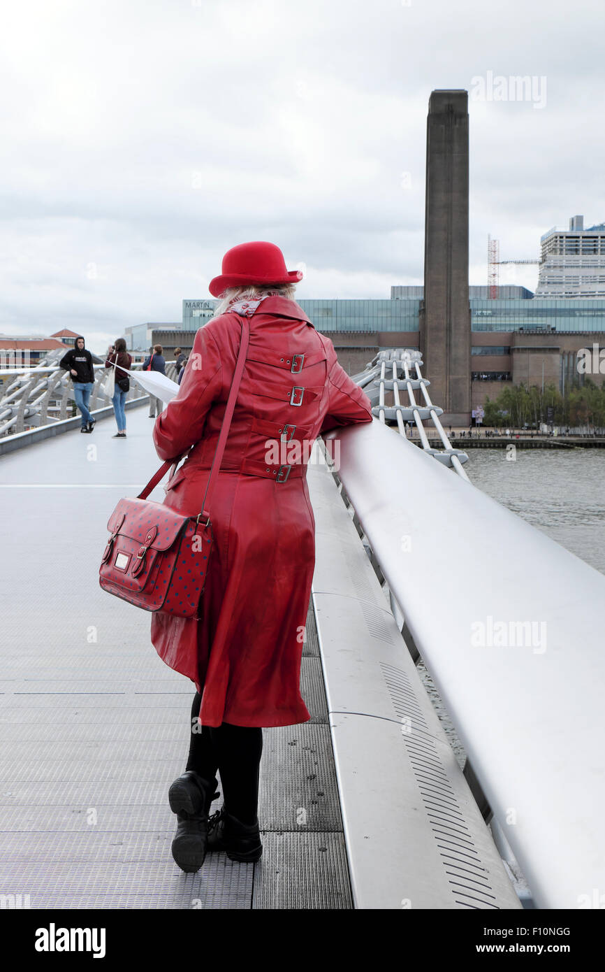 Vista posteriore del turista in rosso cappotto & Bowler cappello in piedi sul Millennium Bridge con vista della Tate di Londra UK KATHY DEWITT Foto Stock