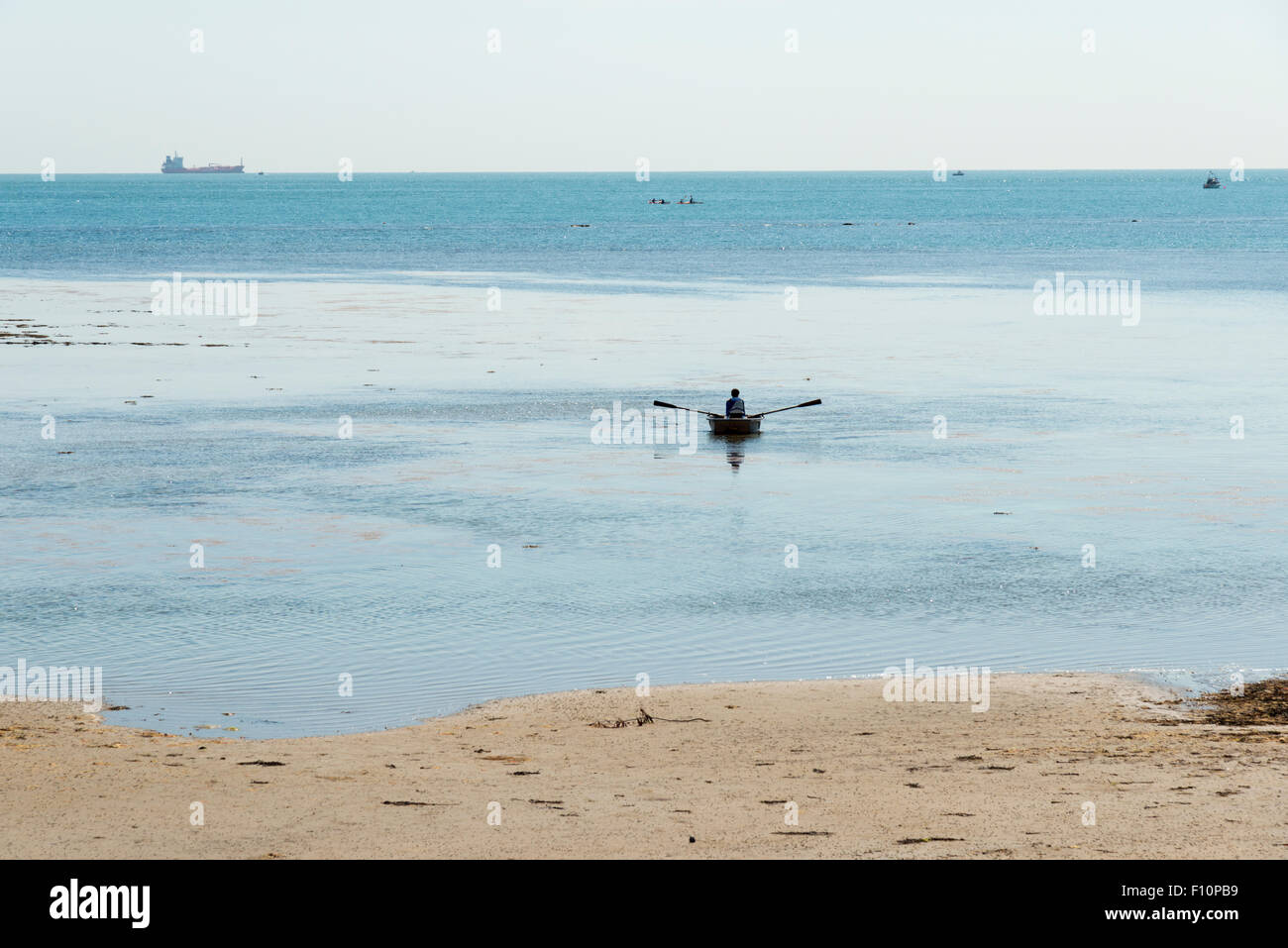 Una persona il canottaggio una piccola barca sulla riva del mare con la bassa marea a Bembridge Isle of Wight REGNO UNITO Foto Stock