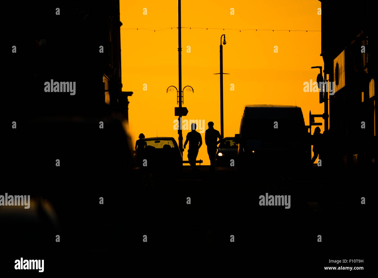 Estate in città: persone in silhouette su una città urbana street al tramonto in una calda serata estiva REGNO UNITO Foto Stock