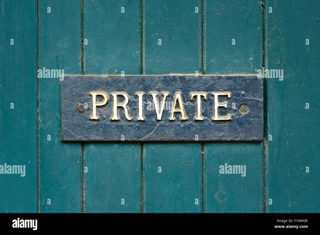 Primo piano di un segno privato su una vecchia porta di legno verniciato di verde Foto Stock