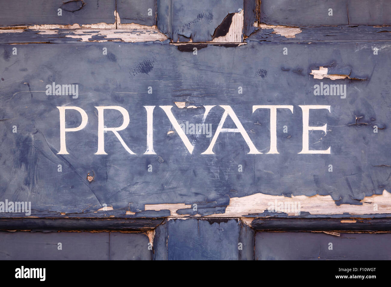 Primo piano di un segno privato su una vecchia porta blu con peeling paint Foto Stock