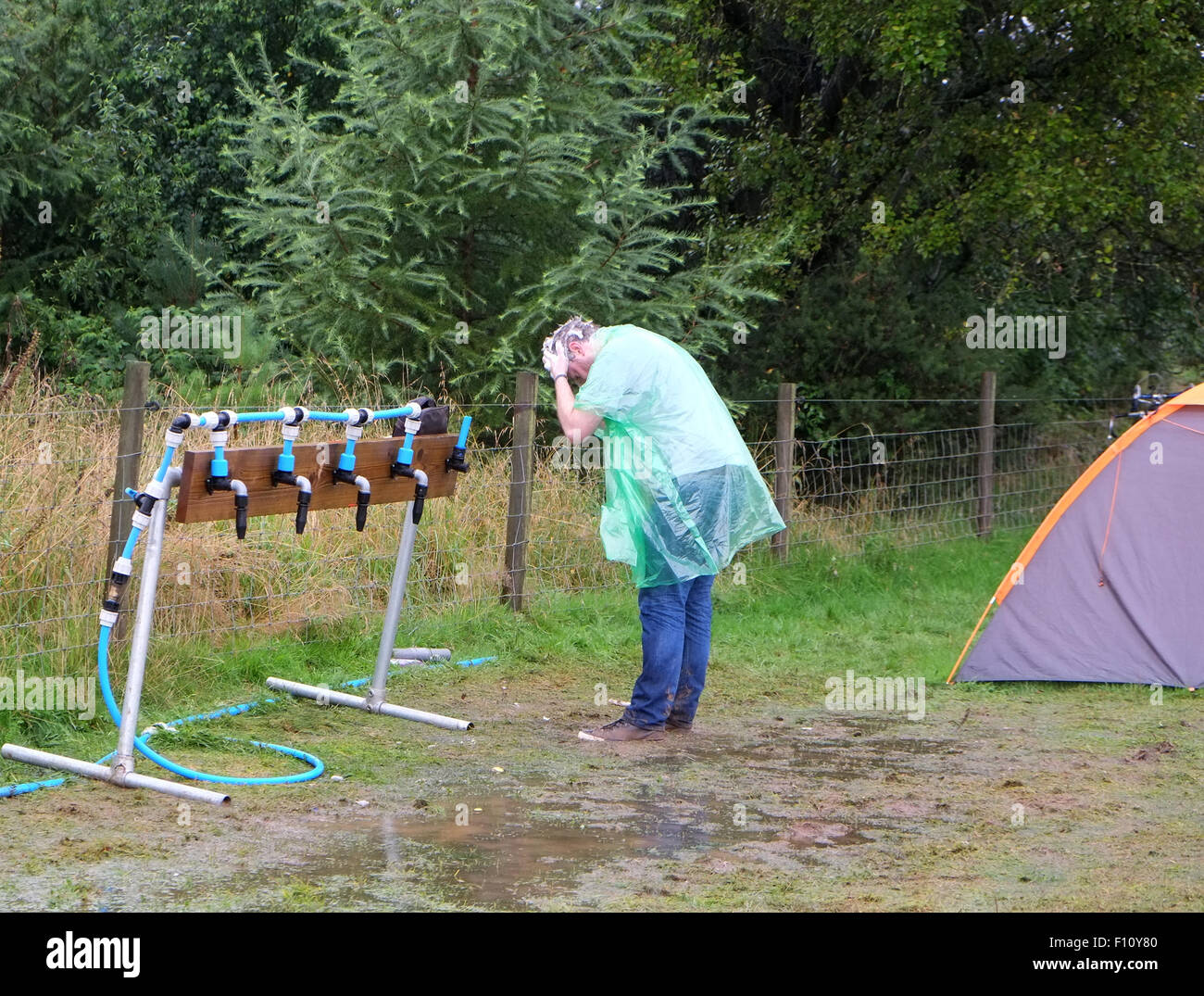 Lavaggio dei capelli a rubinetti quando camping presso il festival di musica sotto la pioggia nel Somerset, Agosto 2015 Foto Stock