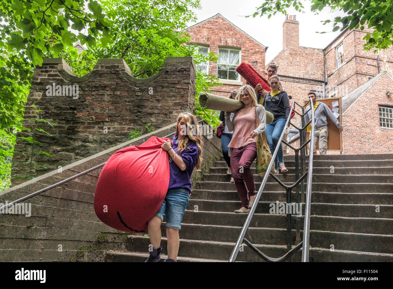 Gli studenti dell'Università di Durham di trasportare oggetti giù alcuni passi dalla Cattedrale di Durham Foto Stock