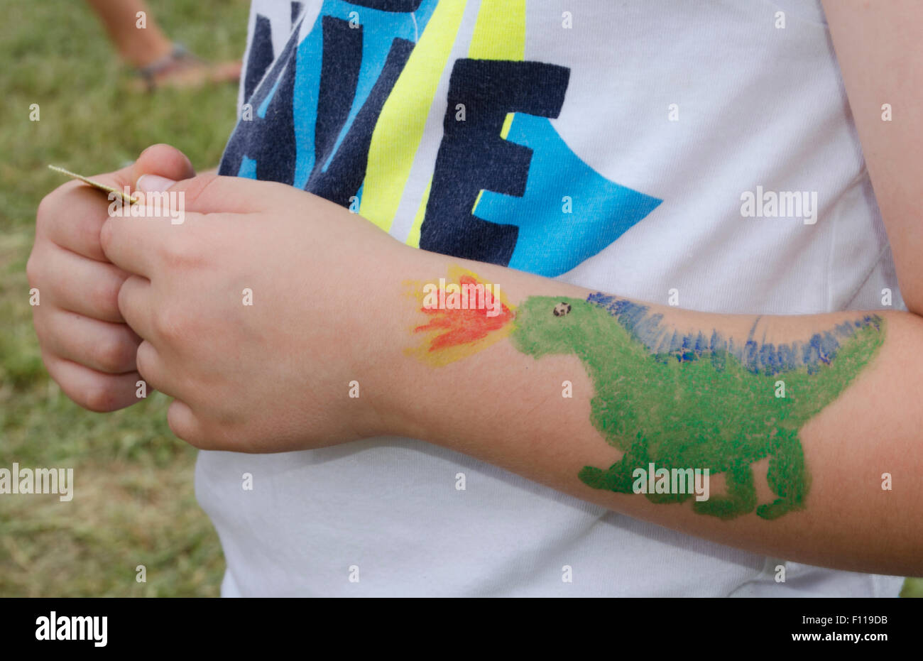 Pittura del viso di un verde drago sputafuoco sul ragazzo del braccio Foto Stock