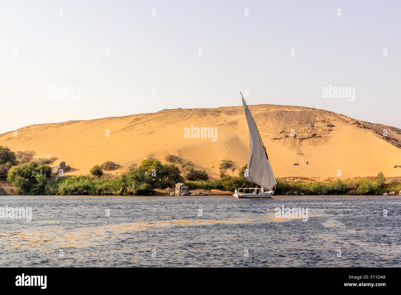 Una vista orizzontale di una scena del Nilo con una barca di fronte di una duna, Egitto Foto Stock