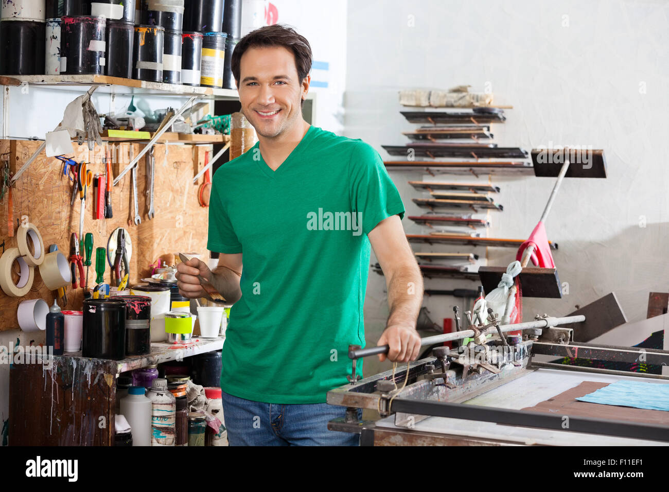 Uomo sorridente holding spazzola nella fabbrica di carta Foto Stock