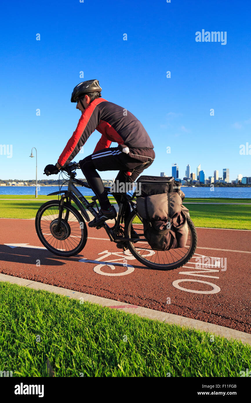 Un maschio ciclista cavalcare giù lungo un percorso in bicicletta con una skyline della città di distanza Foto Stock