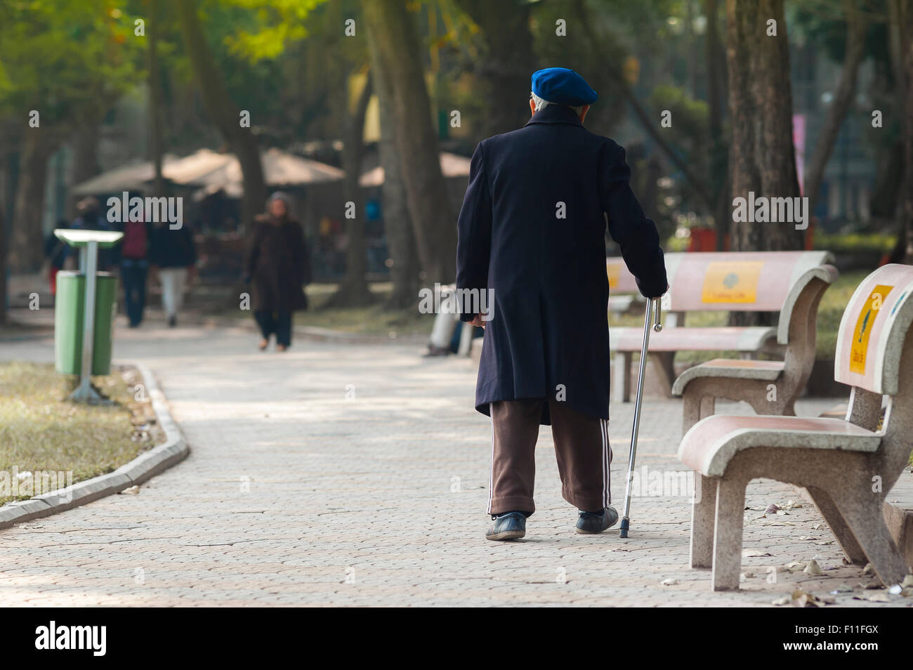 Vecchio uomo che cammina da solo, vista posteriore di un anziano cittadino di Hanoi facendo una passeggiata di mattina presto vicino al lago di Hoan Kiem, Vietnam. Foto Stock