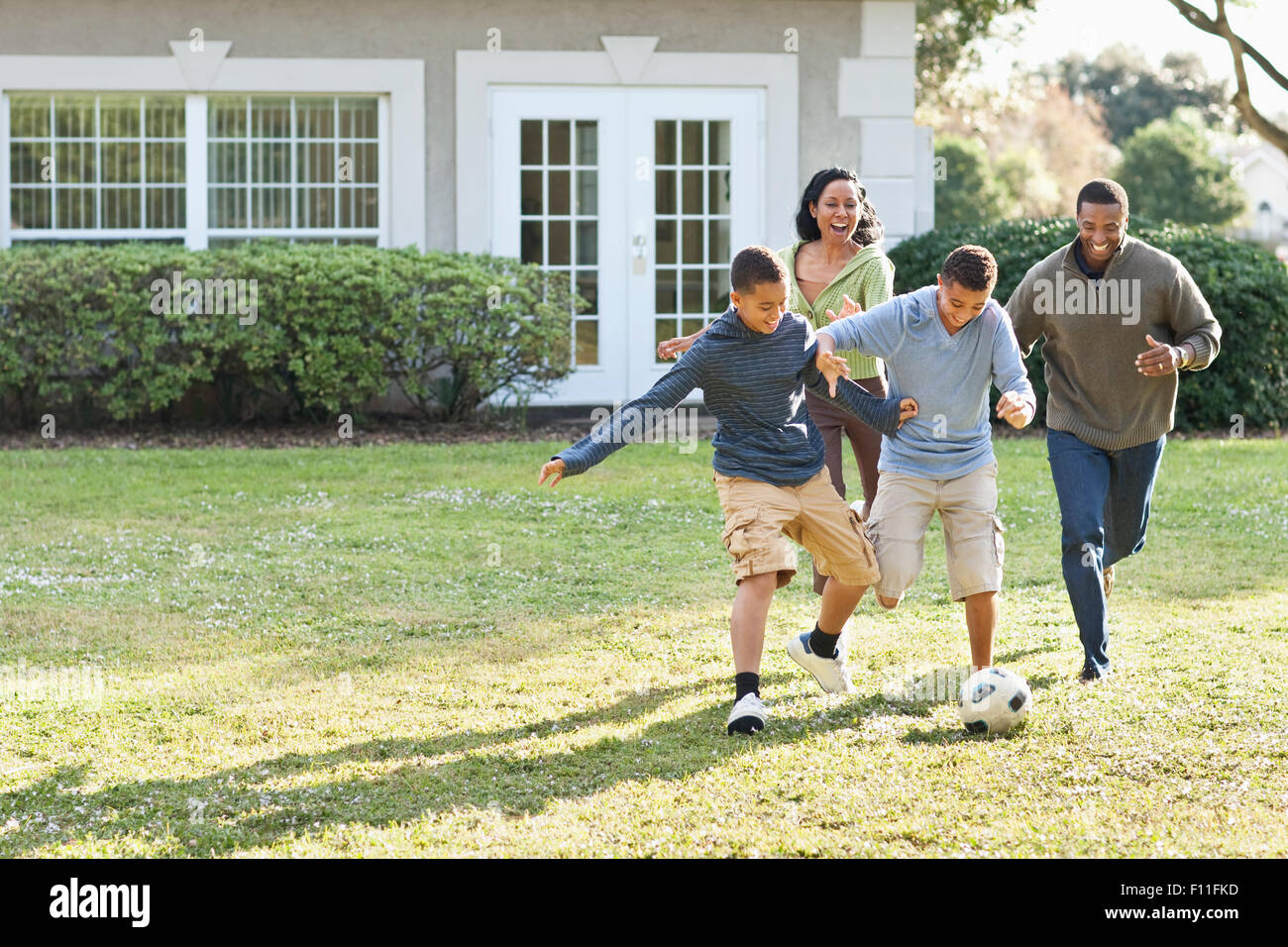 La famiglia che giocano a calcio nel cortile posteriore Foto Stock
