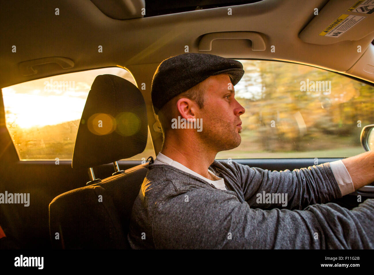 Uomo caucasico auto guida al tramonto Foto Stock