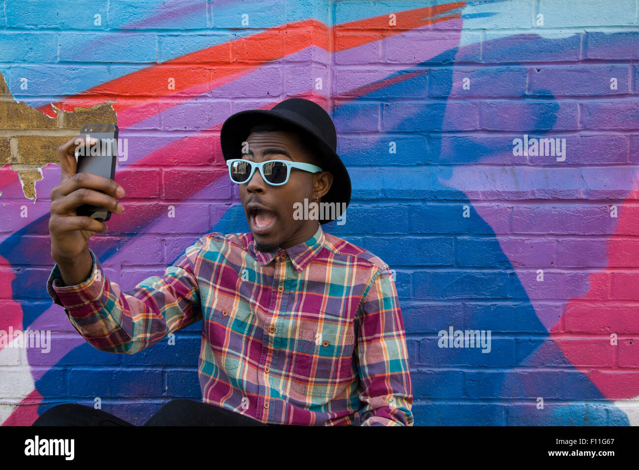 Uomo nero tenendo selfie vicino a parete colorata Foto Stock