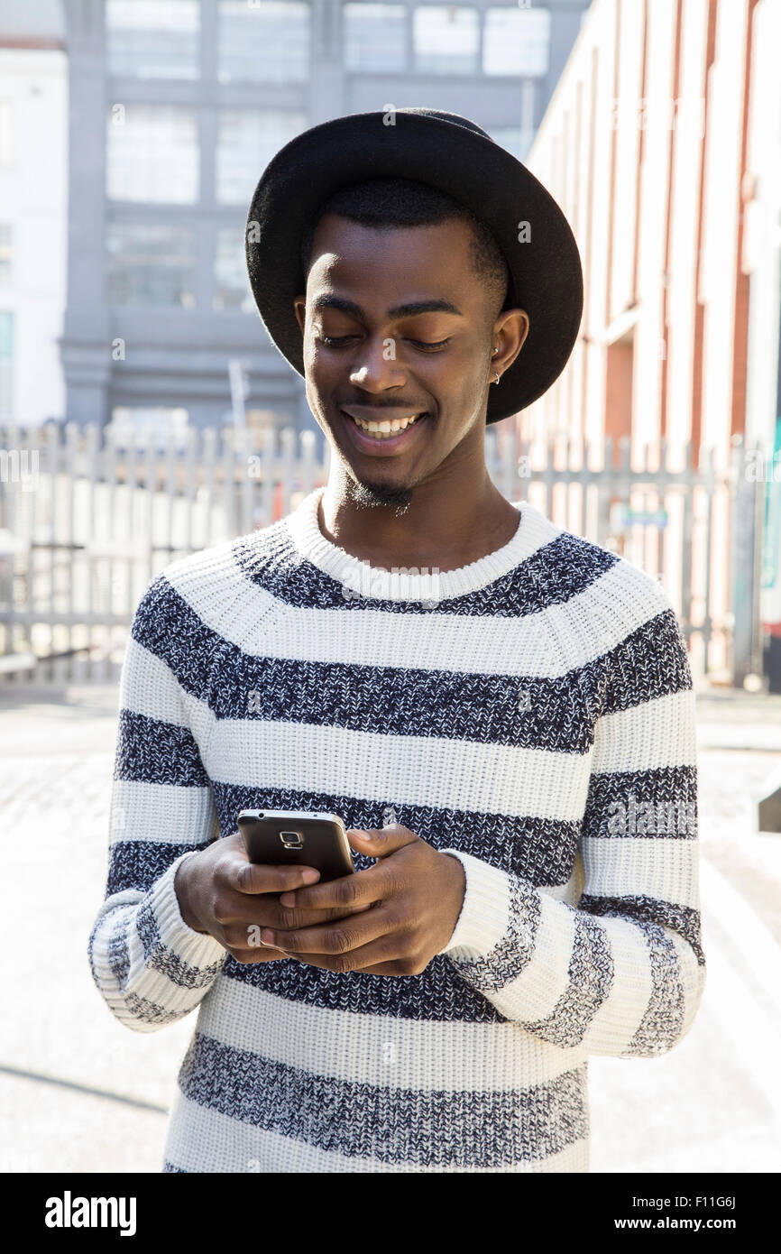 Uomo nero tramite telefono cellulare sul marciapiede urbano Foto Stock