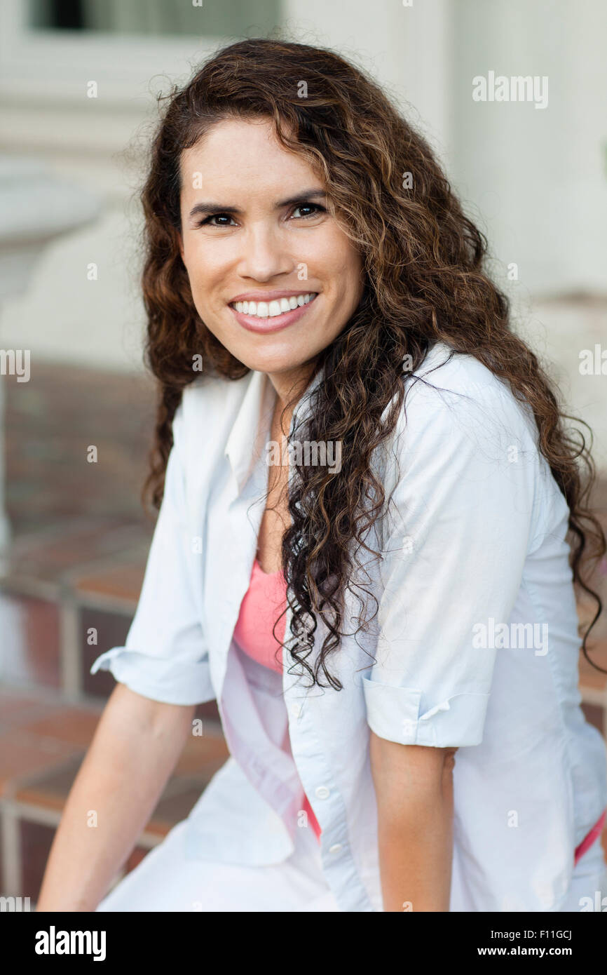 Sorridente ragazza ispanica seduti all'aperto Foto Stock