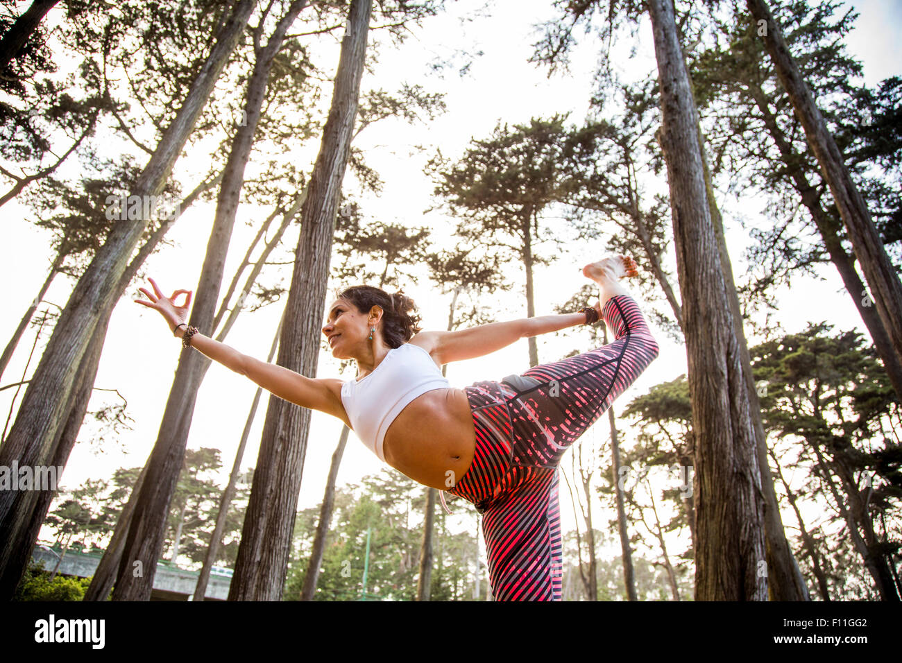 Donna ispanica a praticare yoga in foresta Foto Stock