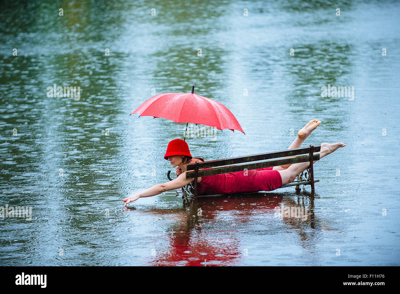 La donna caucasica la posa sul banco nel diluvio Foto Stock