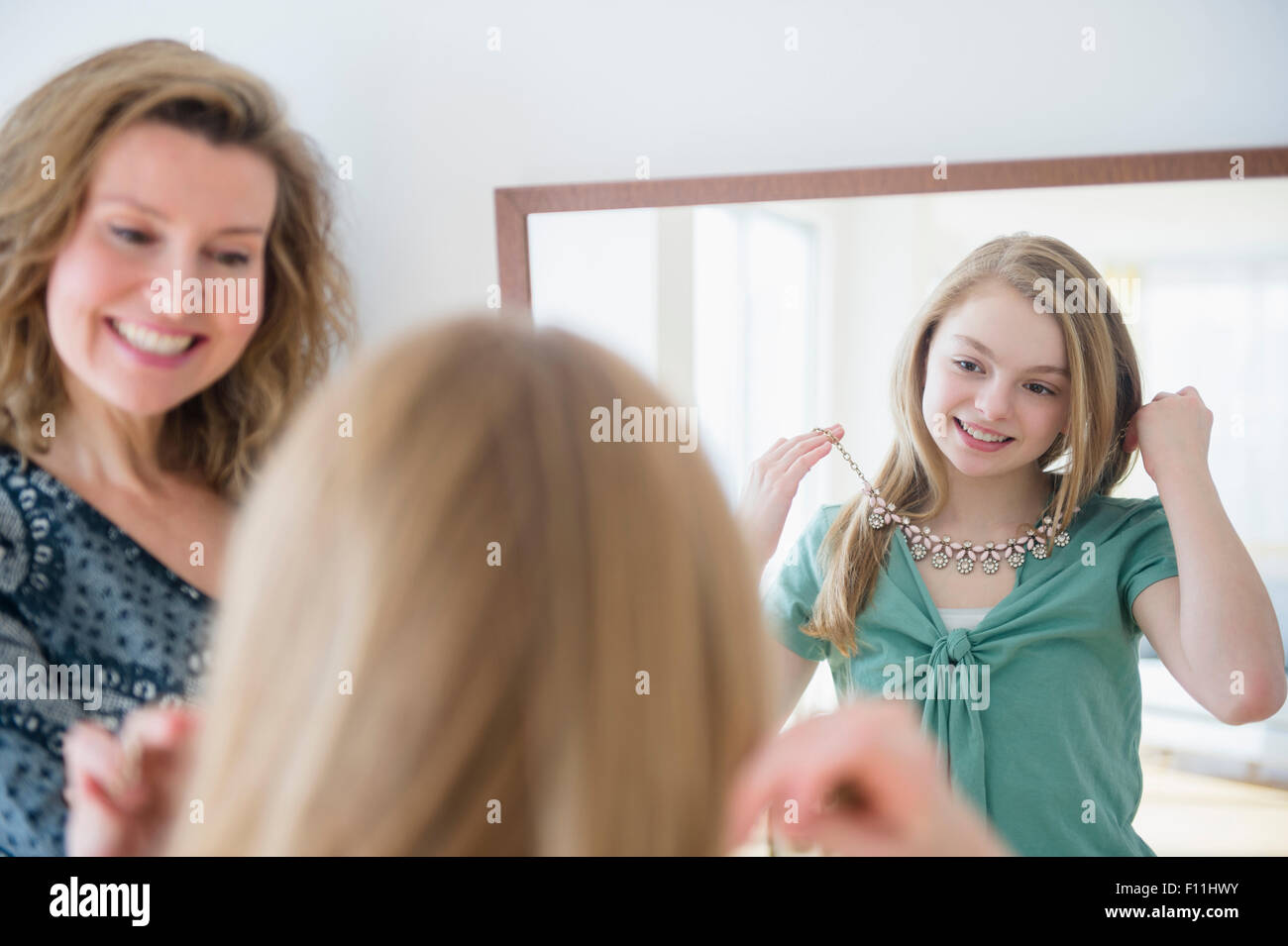 Ragazza caucasica esaminando collana in specchio con madre Foto Stock