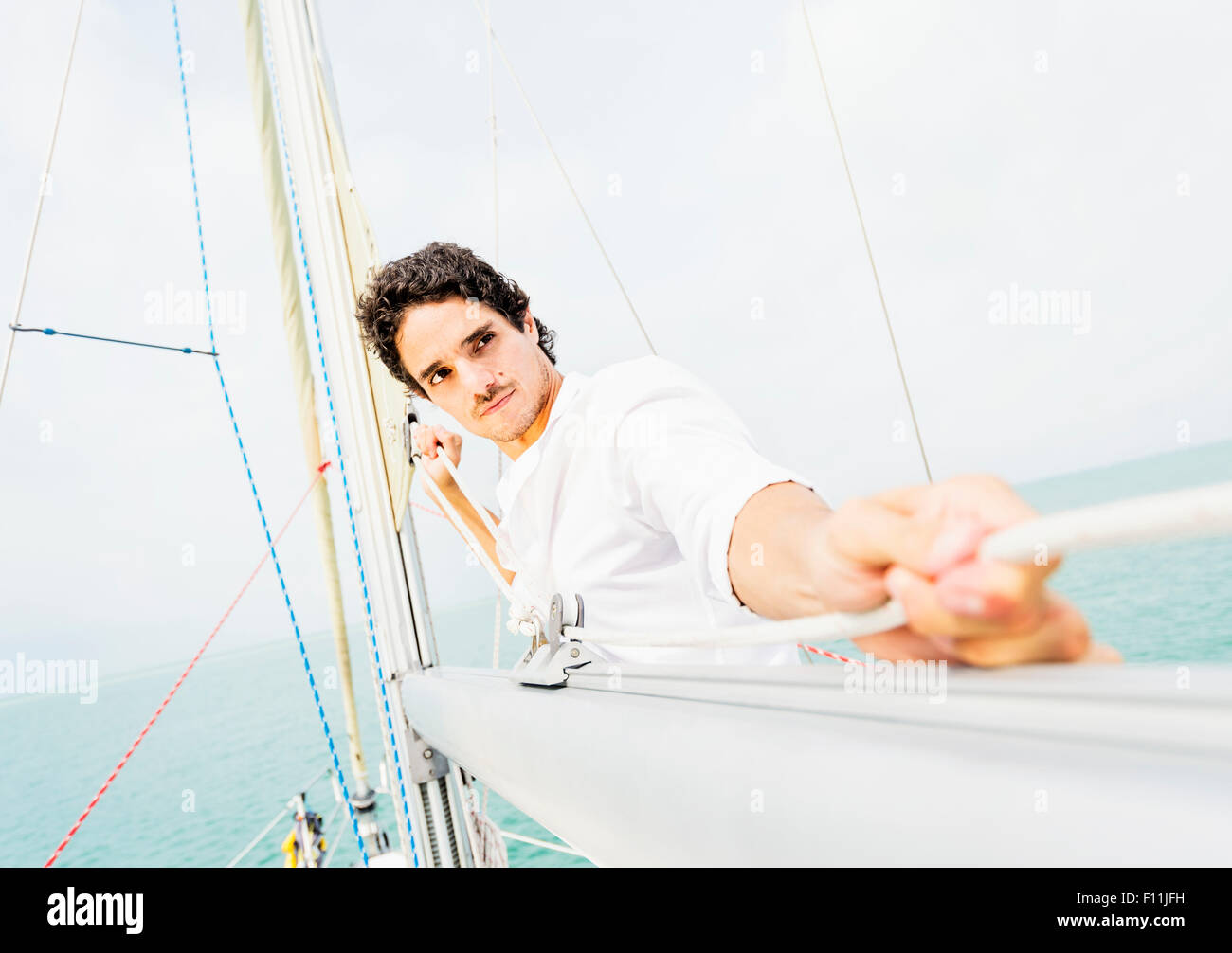 Uomo ispanico manovre di regolazione sulla barca a vela Foto Stock