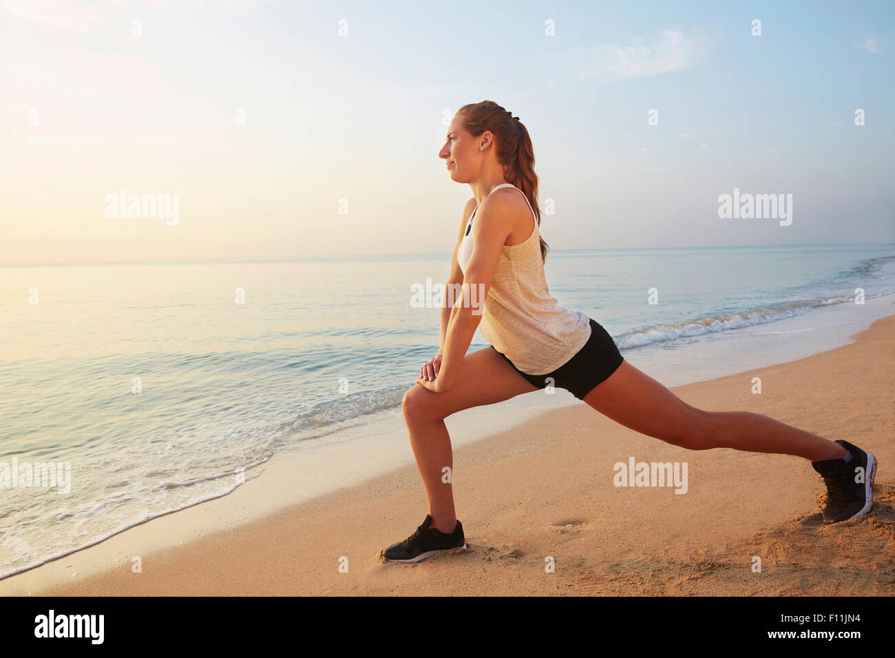 Atleta stiramento sulla spiaggia Foto Stock