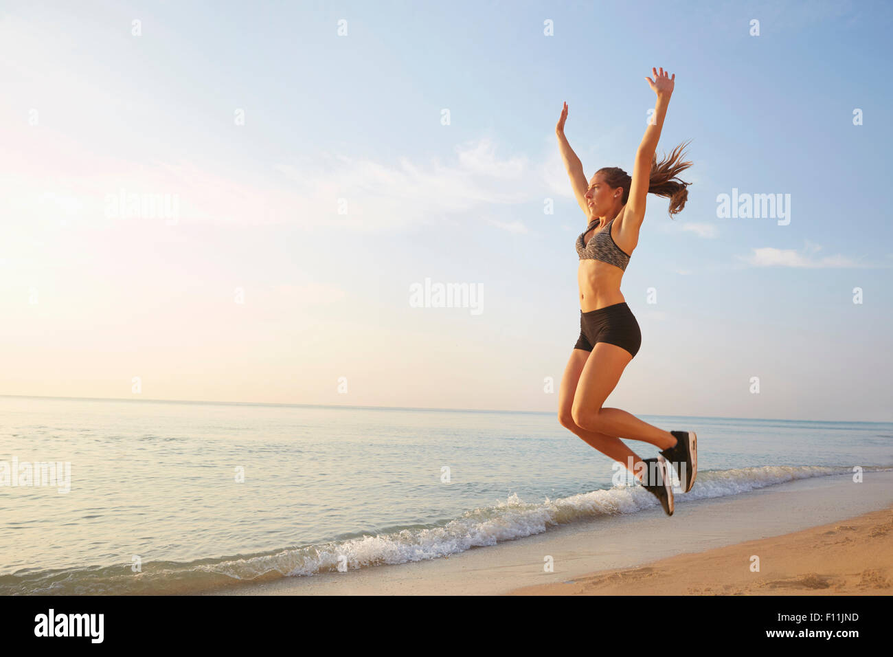 Atleta salti di gioia sulla spiaggia Foto Stock