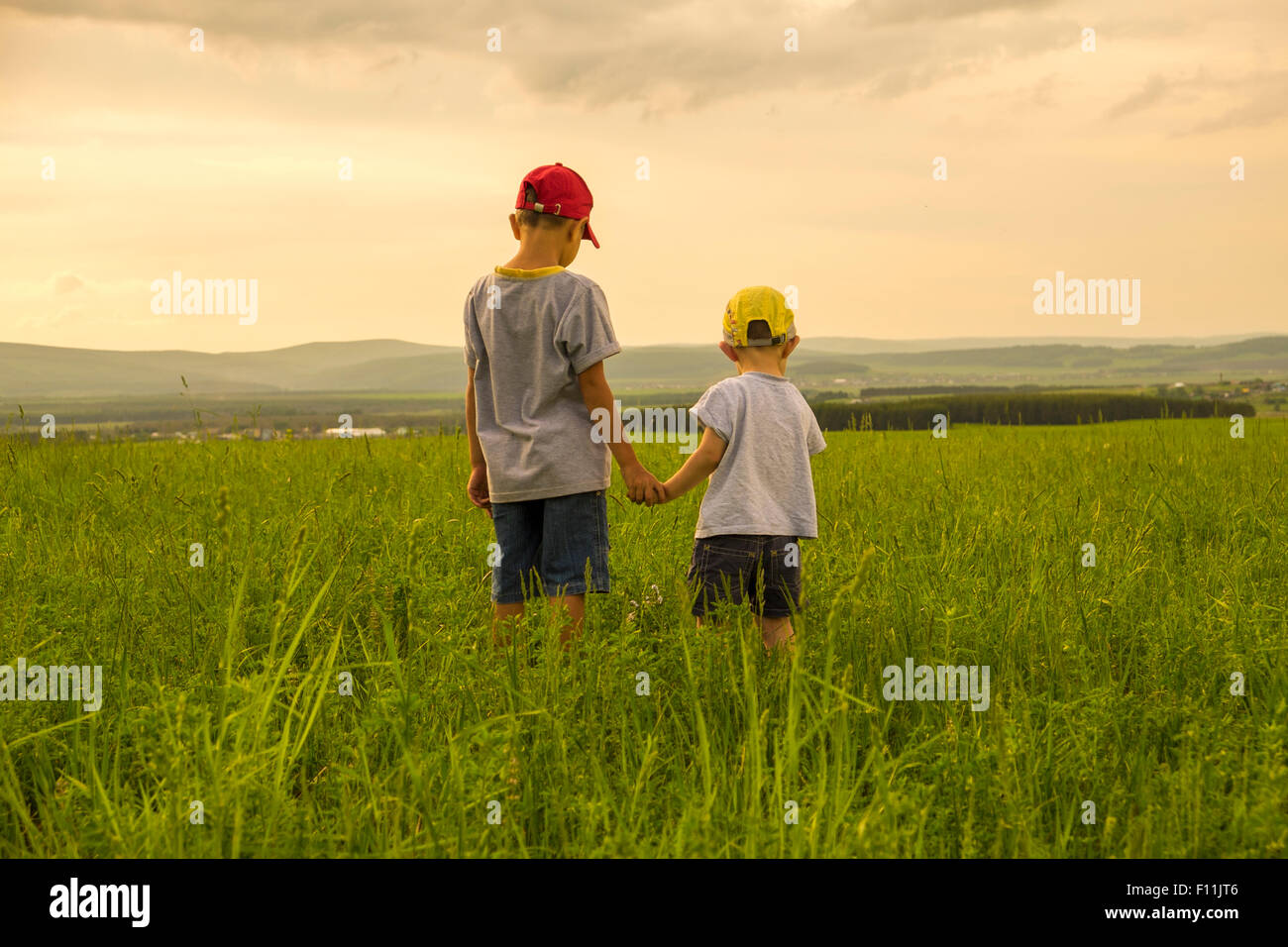Mari fratelli esplorando in campo rurale Foto Stock