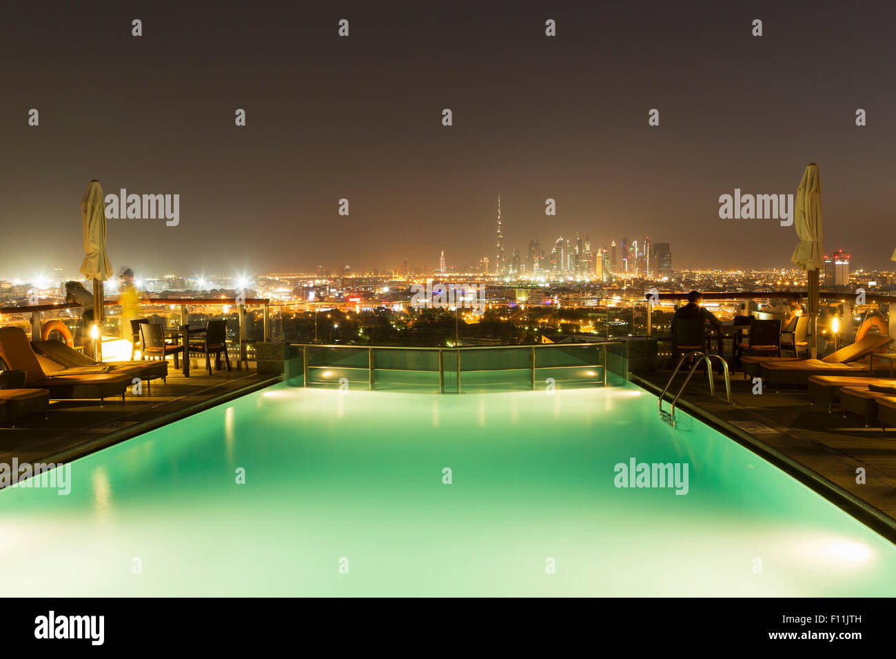 Piscina oltre il paesaggio urbano di notte, Abu Dhabi Emirato, Emirati Arabi Uniti Foto Stock