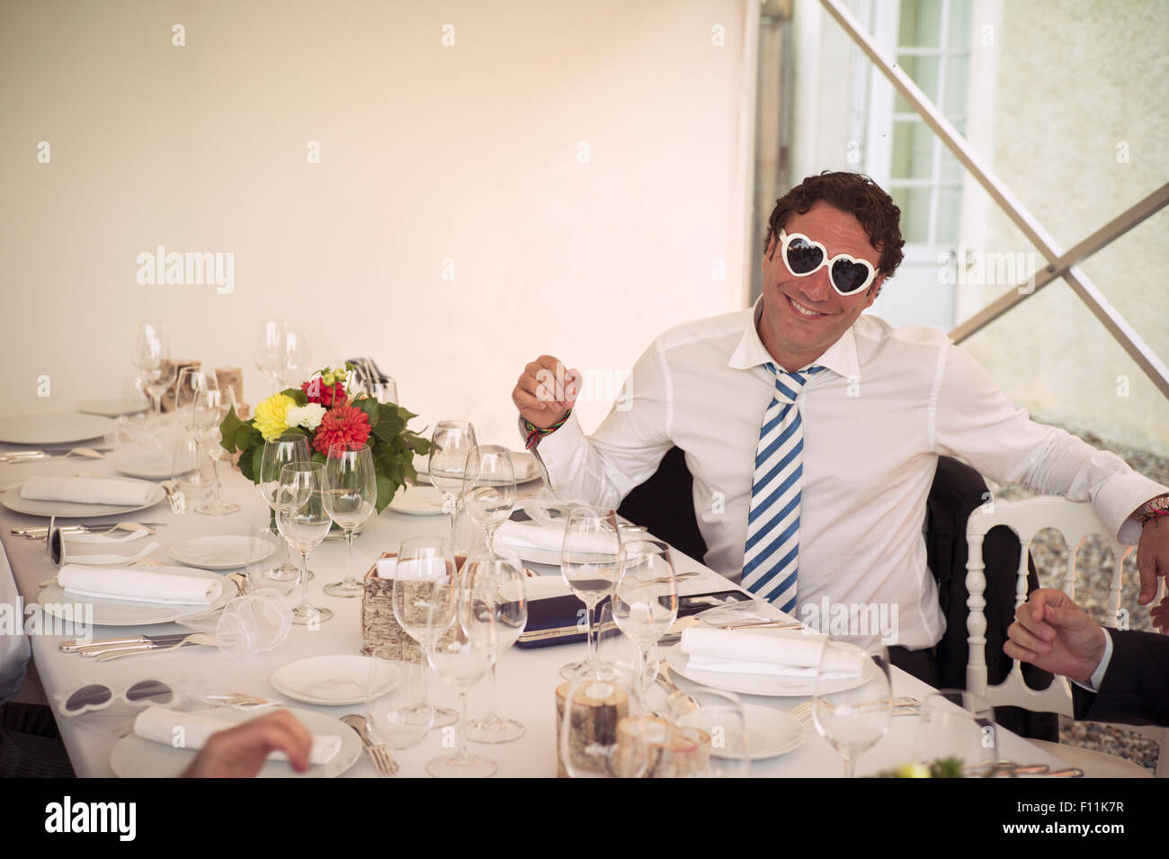 Uomo caucasico indossando a forma di cuore i bicchieri a tavola Foto Stock