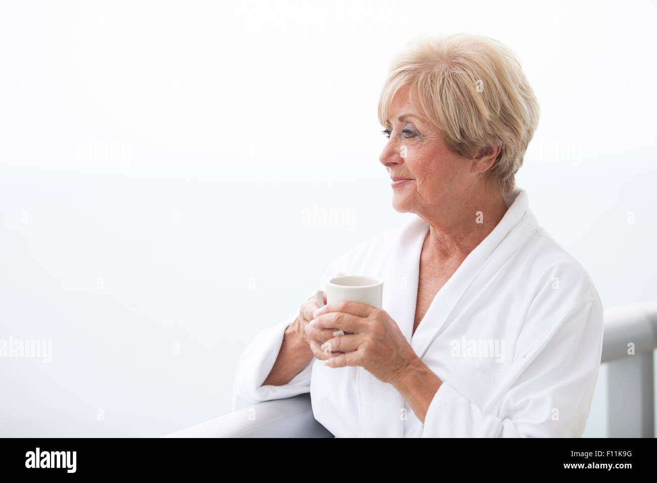 I vecchi donna caucasici di bere il caffè sul balcone Foto Stock