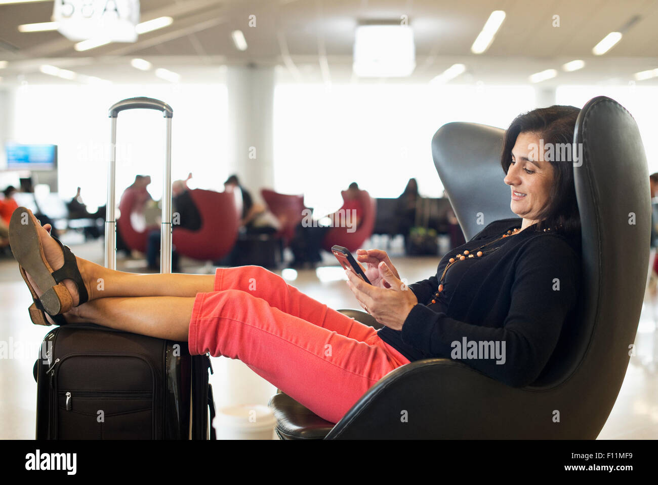 Imprenditrice ispanica utilizzando il cellulare in aeroporto area di attesa Foto Stock