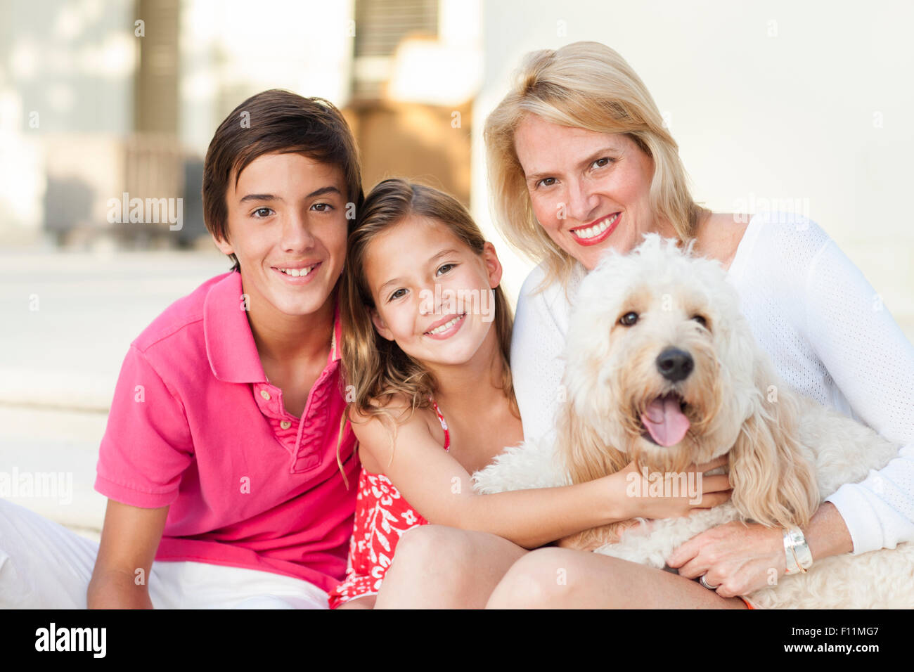 Sorridente madre e bambini in posa con il cane all'aperto Foto Stock