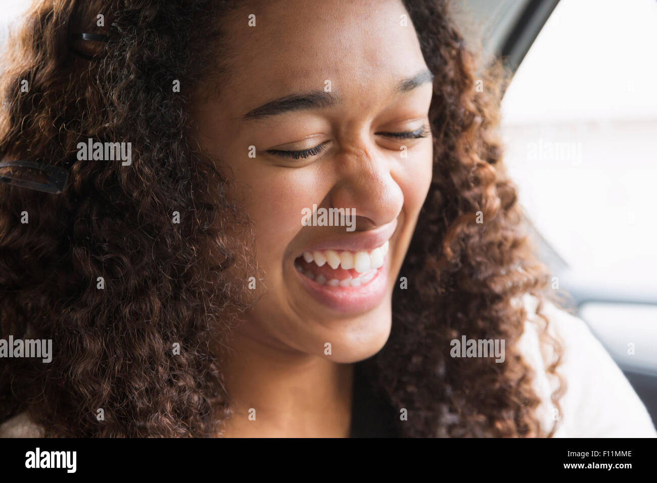 Razza mista ragazza ridere in auto sedile posteriore Foto Stock