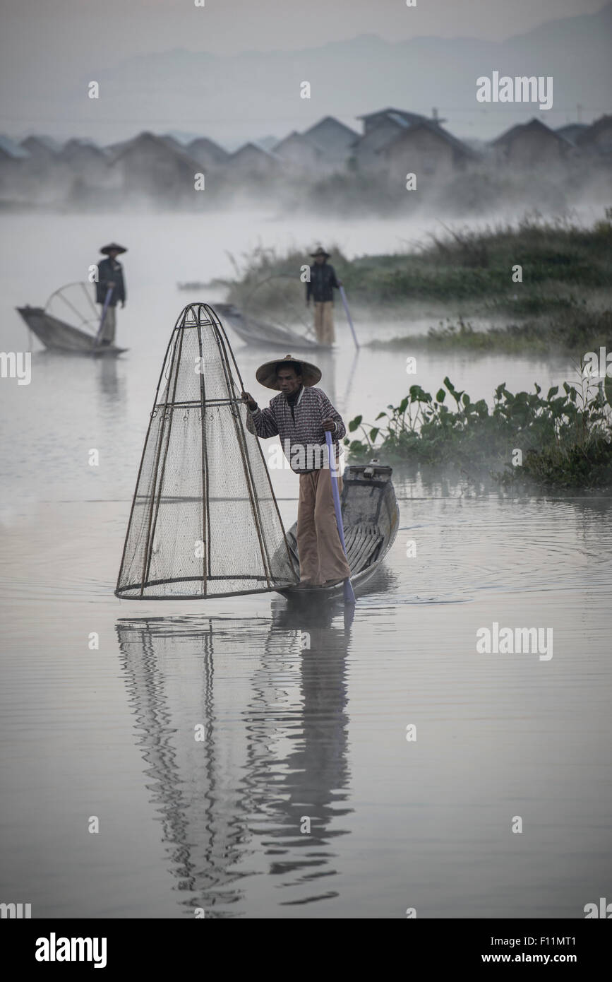 Asian pescatori pesca in canoa sul fiume Foto Stock